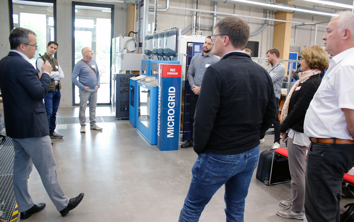 2025-10-17 Webmeldung wvib Fach-Erfa am INES Michael Schmidt Eine Gruppe Menschen steht um eine MicroGrid-Anlage herum